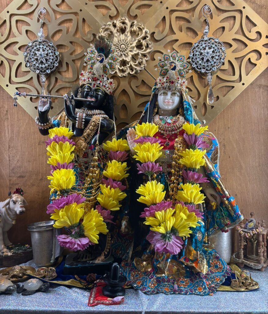 Decorated Hindu deities with yellow and pink flower garlands.